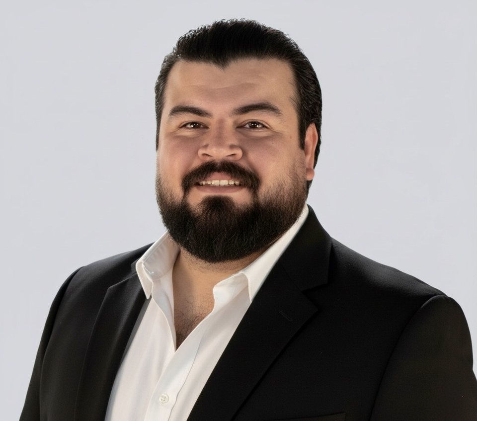 Amirhossein Hosseinpour, smiling, in a black jacket and white shirt